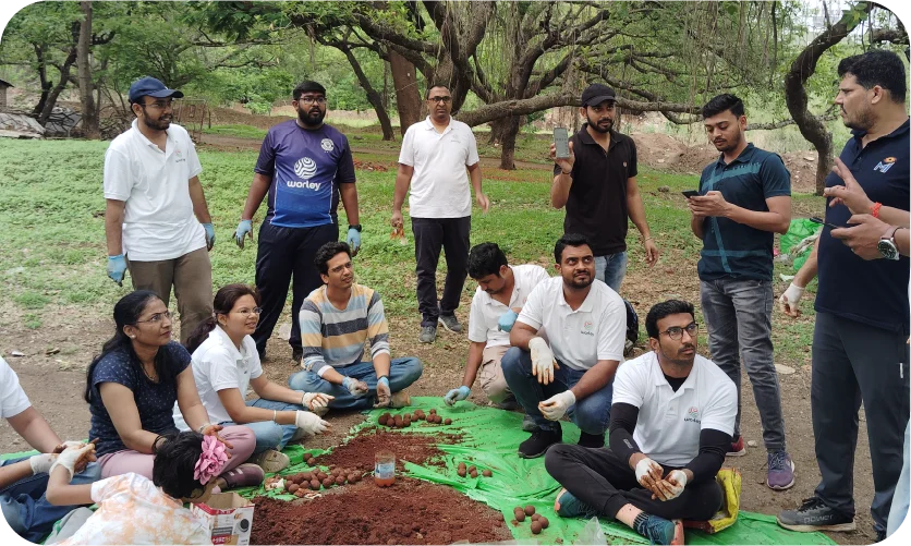 Volunteers mixing soil and materials to prepare seed balls